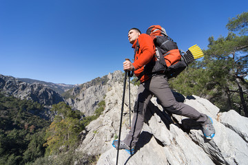 Young man with backpack on a mountain top on a sunny day. 