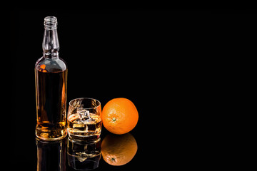 Bottle and glass whiskey with Orange on black background