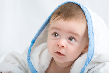 beautiful little baby with big eyes in white towel looking for something