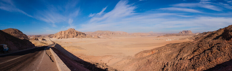 Naklejka premium Panorama of the desert in Egypt and the road stretches to the horizon, against the clear sky