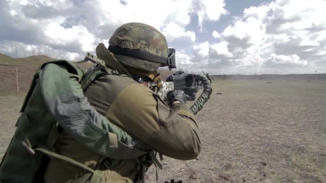 A soldier with a machine gun on a military firing range shooting at a target.