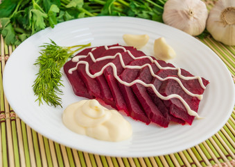 Slices of boiled beets on a white plate with mayonnaise
