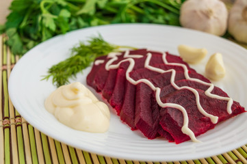 Slices of boiled beets on a white plate with mayonnaise
