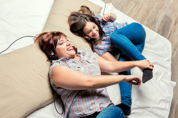 Mother and daughter listening to music in bed.