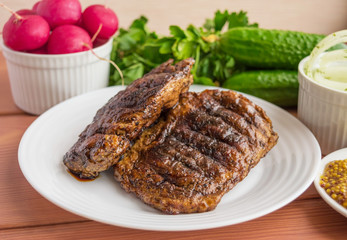 Pork steak, grilled with onion rings and fresh vegetables, herbs