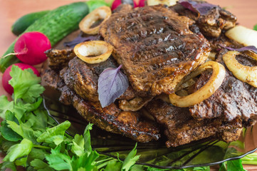 Pork steak, grilled with onion rings and fresh vegetables, herbs