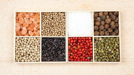 Spices and black rice in a wooden box: red, green and white pepper, sea salt, himalayan salt, allspice and coriander