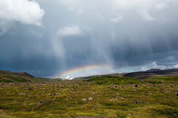 Rain clouds and rainbow with volcanic landscape of moss and rocks, Krafla area, Northern Iceland