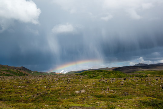 Rain clouds and rainbow with volcanic landscape of moss and rocks, Krafla area, Northern Iceland
