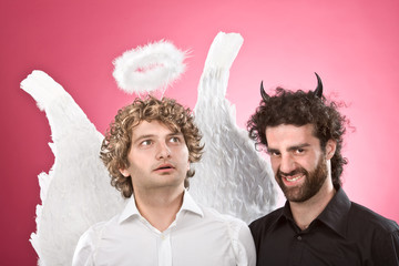 funny white angel and black devil isolated on pink