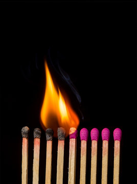 Line of lighted matches on black background