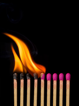 Line of lighted matches on black background