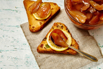Pear jam in a glass on a wooden table. Sandwiches with pear jam and pickled lemons. Healthy breakfast
