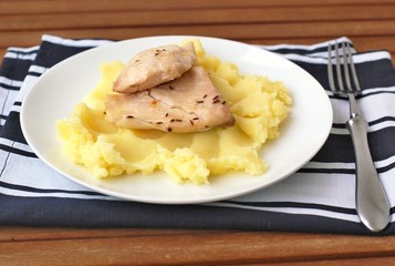 Roasted fish with caraway and mashed potatoes on the cloth and wooden background