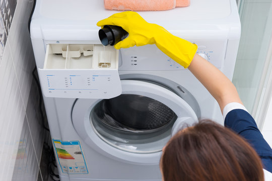 Woman Pouring Fabric Softener Into A Machine