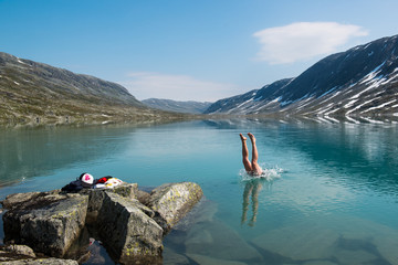 Young man dives into a cold mountain lake, Norway