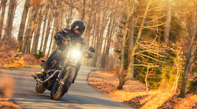 Fototapeta Young man riding chopper on road in forest