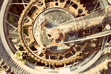 Old dirty motorcycle chain on wheel with rusty metal parts.