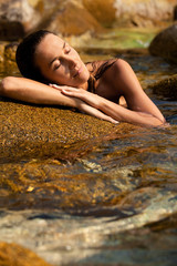 portrait de femme qui se repose au soleil dans l'eau sur un rocher