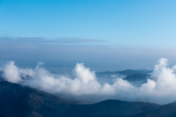 Clouds in mountain valleys under blue sky