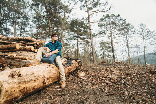 Man sitting on felled wood trunks