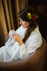 Bride sitting in a chair drinking coffee