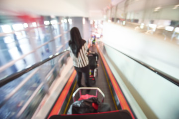 Blur image of people walking down the escalator at airport.