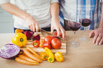 Cropped image of woman cutting tomatoes with husband