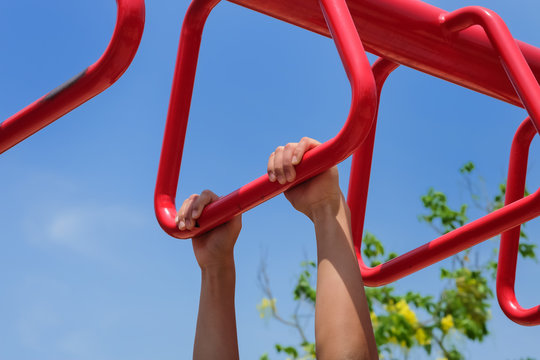 Close up of hanging boy's hands on the brachiating bar