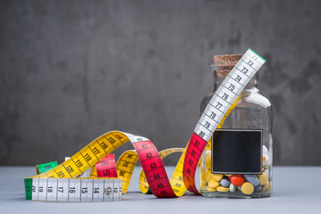 A bottle of diet pills with measuring tape