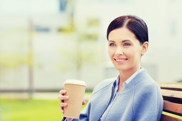 smiling woman drinking coffee outdoors