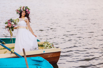 Obraz premium Beautiful brunette posing over beautiful romantic landscape. Bride with wreath of flowers