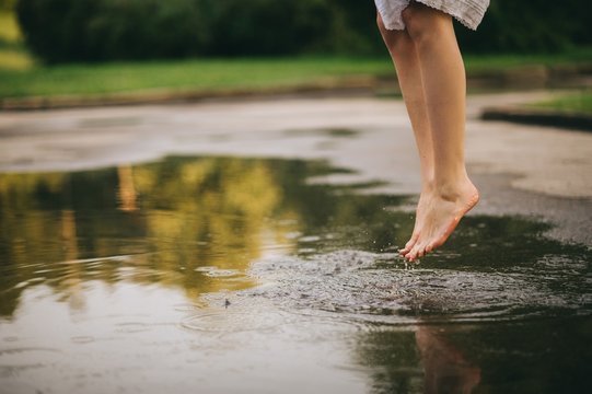 Woman walking barefoot through puddle outdoors