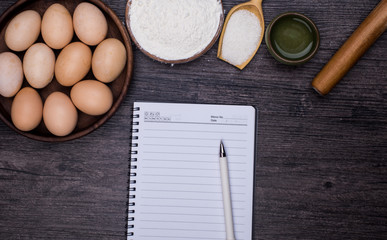 Wooden background with baking ingredients (eggs, flour and rolling pin) over rustic texture. Top view. Space for text. Food or cooking concept.