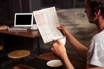 Hipster man reading while drinking coffee
