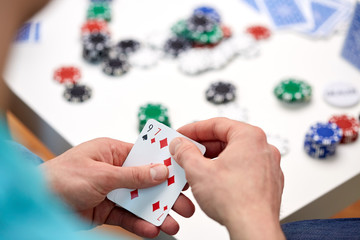 close up of male hand with playing cards and chips