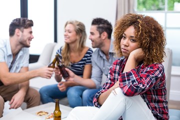 Thoughtful woman with friends enjoying beer in background