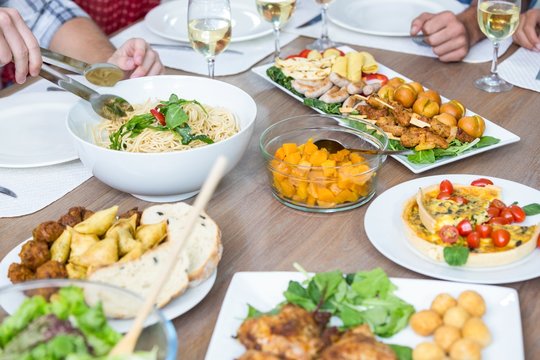 Cropped image of people with food served on table 