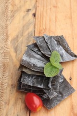 Dried seaweed for cooking on wood background.