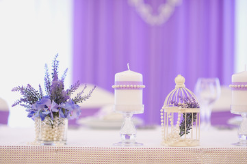 Сиреневый букет, свеча и ваза стоят на столе