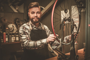 Fototapeta na wymiar Stylish bicycle mechanic doing his professional work in workshop