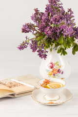 Tea with  lemon and bouquet of  lilac primroses on the table