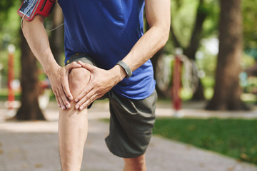 Cropped image of man rubbing his knee after jogging