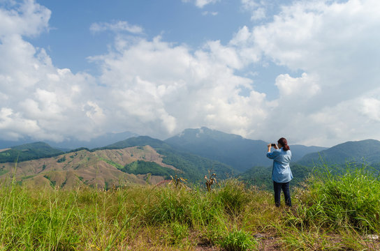 Female traveler with smart phone taking a photo of beautiful landscape at nan thailand