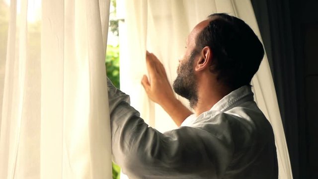 Young man unveil curtains in window, super slow motion 240fps
