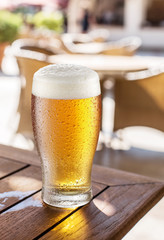 Glass of light beer on the wooden table.