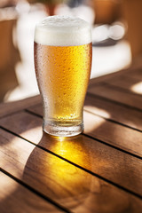 Glass of light beer on the wooden table.