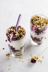 Useful dessert of granola, yogurt and blueberry in glass on a wh