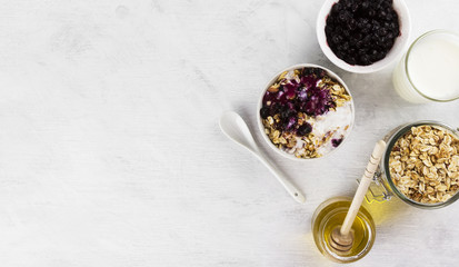 Breakfast: granola, yogurt, honey, blueberry on a white backgrou