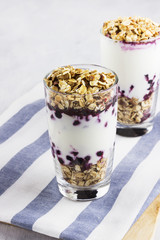 Useful dessert of granola, yogurt and blueberry in glass on a wh